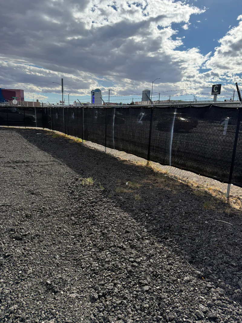 Privacy-screened chain-link perimeter fence along the graded gravel Personal Storage Lot for RV and boat storage in Las Vegas